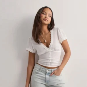 Vit croppad blus med spetskant - Säljer en vit croppad blus med korta puffärmar och v-ringning. Aldrig använd i storlek 38. Köpare betalar frakt. Inte mina bilder.