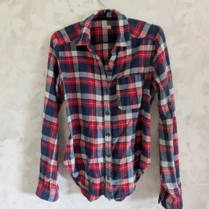 Rutig röd och blå skjorta Hollister XS - Riktigt snygg rutig skjorta från Hollister i rött, blått och vitt. Köpt begagnad och är fortfarande i bra skick, sparsamt använd. Tillverkad i mjuk bomull. 