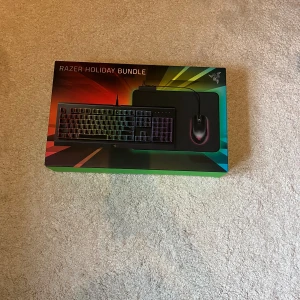 Razer Holiday Bundle (Cynosa Chroma, Abyssus Essential, Goliathus Chroma) - Razer Holiday Bundle med Cynosa Chroma-tangentbord, Abyssus Essential-mus och Goliathus Chroma-musmatta. RGB-belysning, perfekt för gaming. Allt i originalförpackning, ser oanvänt ut och i nyskick. Komplett set för en snygg och responsiv spelupplevelse.