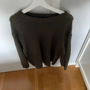 Olivgrön stickad tröja från 157 - Mysig olivgrön stickad tröja från 157 i storlek M. Tröjan har en enkel och avslappnad passform med rund halsringning och långa ärmar. Perfekt för lager-på-lager under kyliga dagar.