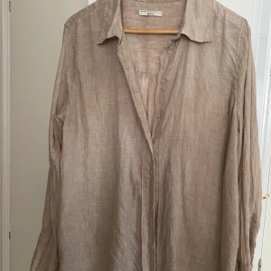 Linneskjorta från Gina Tricot  - Säljer en beige skjorta i linne från Gina Tricot. Skjortan har klassisk krage, knappar framtill och långa ärmar. Ni får ursäkta att den är ostruken på bilden hehe! I jättebra skick annars.