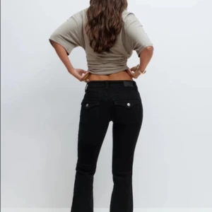 Svarta bootcut jeans från Gina Tricot - Svarta jeans från Gina Tricot med bootcut-modell och klassisk femficksdesign. Jeansen har låg midja och raka ben som släpper ut lite vid ankeln. Tillverkade i stretchig bomullsblandning för en bekväm passform.