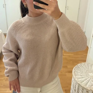Beige stickad tröja från H&M - Supermysig beige stickad tröja från H&M i storlek XS. Tröjan har en hög, ribbad krage och är långärmad. Perfekt för höst- eller vinterstil. Snyggt grovstickat material som känns både trendigt och bekvämt.