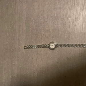 Silverfärgad klocka från Mockberg - Stilren klocka från Mockberg i silverfärgat metallarmband och rund urtavla med romerska siffror. Klassisk design med länkarmband och vit urtavla, perfekt för dig som gillar en tidlös look. Klockan har en elegant och minimalistisk känsla. Pris kan diskuteras!