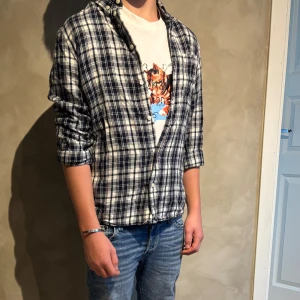 Vit Maison Margiela t-shirt med kattmotiv - Vit t-shirt från Maison Margiela med tryck av en katt och siffror på bröstet. Klassisk passform och rund hals. Tillverkad i mjuk bomull och har korta ärmar. Perfekt för dig som gillar unika och lekfulla prints. Legat i garderoben pga förstor. Pris kan diskuteras, hör av er vid fler frågor eller funderingar!