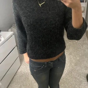Mörkgrå stickad tröja från Monki - Mysig mörkgrå stickad tröja från Monki i storlek S. Tröjan har en lite lös passform, trekvartsärmar och är tillverkad i ett fluffigt, stickat material. Perfekt för kyliga dagar och enkel att matcha med jeans eller kjol. Finns ett litet hål på sidan men inget som märks när man har på sig den❤️