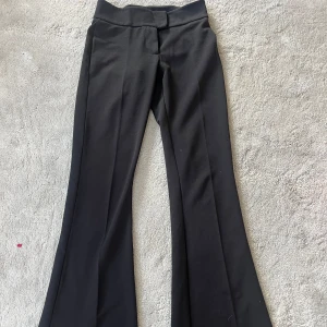 Svarta bootcut kostymbyxor Gina Tricot - Svarta kostymbyxor från Gina Tricot i bootcut-modell med medelhög midja. Byxorna är stretchiga och sköna, därav sitter dem inte obekvämt tajt runt benen