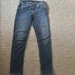 Blå Replay jeans straight fit - Säljer ett par klassiska blå jeans från Replay med raka ben och normal passform. Jeansen har fem fickor, snygga detaljer på bakfickorna och en läderpatch med Replay-logga i midjan. Perfekta till vardags och lätta att matcha med det mesta.