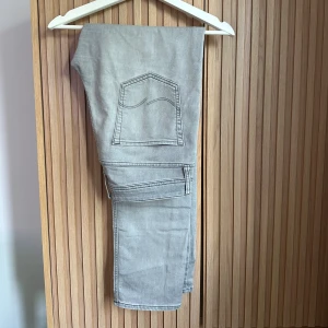 Grå jeans från Jack & Jones, 33/34 - Snygga grå jeans från Jack & Jones i klassisk modell. Jeansen har raka ben, femficksdesign och diskreta sömmar på bakfickorna. Tillverkade i mjuk bomullsdenim som är skön att bära hela dagen. Perfekt för dig som gillar stilrena och enkla jeans.