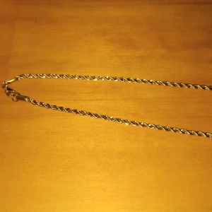 Guldlänk  - Snyggt halsband i guldfärg med tvinnad kedja och klassiskt lås. Perfekt för att ge din outfit lite extra bling. Passar dig som gillar stilrena och tidlösa smycken med en twist. 50mm långt