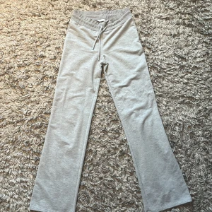 Grå mjukisbyxor från 157, XS - Grå mjukisbyxor från 157 i storlek XS. Byxorna har rak passform, resår i midjan och snörning framtill. Tillverkade i mjukt bomullsmaterial som är skönt mot huden. Perfekta för chill dagar eller när du vill vara bekväm.