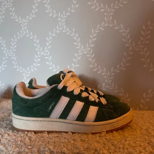 Adidas Campus & Gazelle sneakers mocka - Två par klassiska Adidas sneakers: ett par gröna Campus med vita ränder och snörning i mocka, samt ett par mörkblå Gazelle med vita detaljer och svarta snören, även de i mocka. Använda några få gånger. Strl: 41, 1/2                                                          400kr/st