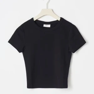 Svart croppad t-shirt - En stilren svart croppad t-shirt med rund halsringning och korta ärmar. Perfekt att matcha med jeans eller kjol för en enkel och snygg look. T-shirten har en tight passform och är tillverkad i mjuk bomull.