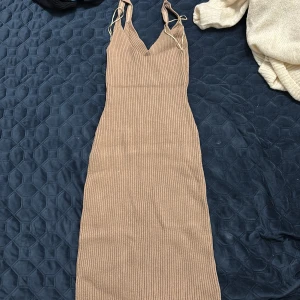 Beige ribbad långklänning Gina Tricot - Säljer en beige ribbad långklänning från Gina Tricot. Klänningen har smala axelband, v-ringning och är figurnära i modellen. Perfekt för dig som gillar en enkel men snygg look. Materialet är stretchigt och bekvämt.
