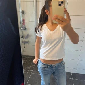 Vit Calvin Klein T-shirt - Säljer en vit V-ringad T-shirt ifrån Calvin Klein. Jättesnygg basic tröja som går lätt att styla. För dig som gillar en basic men ändå avslappnad look.