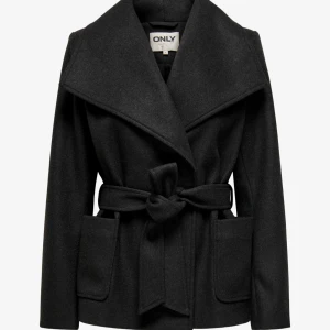 Svart kappa med bälte från ONLY - Stilren svart kappa från ONLY med bred krage och knytskärp i midjan. Jackan har stora fickor framtill och är tillverkad i ett ullblandat material. Perfekt för dig som vill ha en klassisk look med modern touch. Jacka är i princip helt ny, har endast använt den ett fåtal gånger.