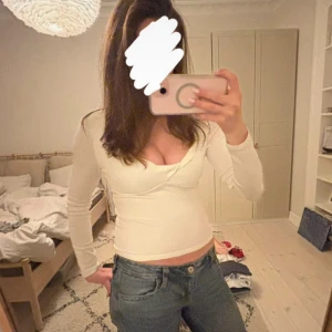 Vit omlottopp från Gina Tricot - Säljer en vit långärmad topp från Gina Tricot i omlottmodell med v-ringning. Toppen är croppad och har en figurnära passform, perfekt till jeans eller kjol. Tillverkad i mjuk bomull som känns skön mot huden.