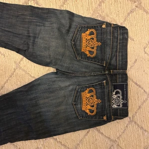 Victoria Beckham jeans med guldbrodyr - Snygga mörkblå jeans från Rock & Republic/Victoria Beckham med ikoniska guldiga kronbroderier.Köpta i New York förra året för 300$ Midjemåttet är 25 inches/32 cm tvärs över🩷innbenslängden 82
