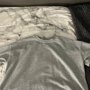 Grå basic t-shirt från Pieces - Enkel och stilren grå t-shirt från Pieces i storlek XS. T-shirten har rund halsringning och korta ärmar, tillverkad i mjuk bomull för en skön känsla. Perfekt till jeans eller shorts för en avslappnad look.