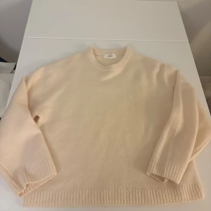 Beige stickad tröja från Gina Tricot - Mysig gul stickad tröja från Gina Tricot i ullblandning. Tröjan har rund halsringning, ribbade muddar och en klassisk, enkel design som är lätt att matcha. Perfekt för lager-på-lager under kyliga dagar.