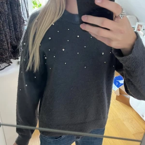 Mörkgrå stickad tröja med pärlor H&M - Mysig mörkgrå stickad tröja från H&M, dekorerad med små pärlor. Tröjan har rund halsringning och långa ärmar, perfekt för kyliga dagar. Som ni ser på bild tre är den smått nopprig, men inget som jag anser syns på! Storlek xs💞