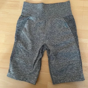 Gråa träningstights  - Säljer ett par grå, tighta träningstights shorts från Gymshark i storlek XS. De är högmidjade! Perfekta för gymmet eller löpning, med stretchigt och bekvämt material. 