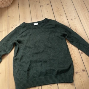 Mörkgrön stickad tröja från Vila - Mysig mörkgrön stickad tröja från Vila i storlek S. Tröjan har rund halsringning, ribbade muddar vid ärmslut och nederkant samt lång ärm. Perfekt för lager-på-lager och chill dagar.