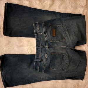 Wrangler blå bootcut jeans - Snygga blå jeans från Wrangler med klassisk bootcut-jeans knappt använda. Materialet är robust denim i bomull och de har en Wrangler-lapp på bakfickan. 72cm i midja. 77 cm i innerben