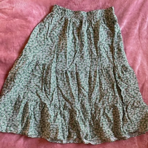 Långkjol  - Supersöt grön kjol med blommor!! Den går ungefär ner till knäna så den är medium length. Passar utmärkt till en härlig sommardag 😎resåren i midjan är relativt stretchig så trots att den är storlek s hade den nog passat m också!!