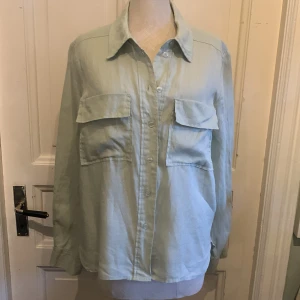 Ljusgrön overshirt i linne - Snygg ljusgrönovershirt i linne med klassisk krage och stora bröstfickor med lock. Skjortan har knäppning framtill och långa ärmar med manschett. Perfekt att slänga över en t-shirt för en chill look.