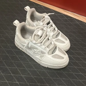 Vita sneakers herr ( REP!) - Säljer ett par vita sneakers med coola detaljer och logga på sulan. Skorna har meshpaneler, skinnpartier och snörning. Hål i botten annars bra och smutsigta skor 