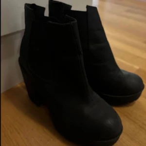 Svarta boots med klack Storlek 39 - Snygga svarta boots med hög klack och platåsula. Skorna har rund tå och är tillverkade i ett material som liknar skinn. Perfekta för att lyfta din outfit med en stilren och edgy vibe.