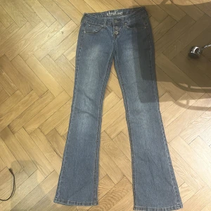 Blå bootcut jeans från Ultra Love - Snygga blå jeans från Ultra Love med bootcut passform och låg midja. Jeansen har tre knappar framtill, klassiska fickor och coola broderade detaljer på bakfickorna. 