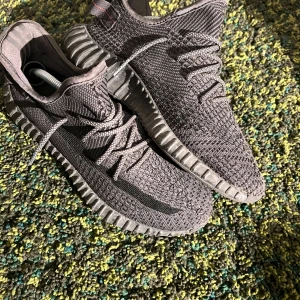 Adidas Yeezy Boost 350 V2 svart - Säljer ett par Adidas Yeezy Boost 350 V2 i svart. Skorna har stickad ovandel i syntet, klassisk rand på sidan och grov sula med boost-dämpning. De har snörning och en sportig, modern look med diskreta röda detaljer på hälen.