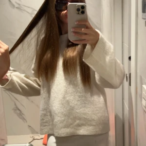 Vit stickad tröja - Mysig vit stickad tröja med breda, långa ärmar och avslappnad passform. Perfekt för lager-på-lager och chill dagar. Enkel och stilren design som funkar till det mesta. Snygg att matcha med jeans eller kjol.