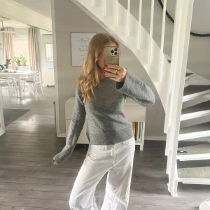 Grå stickad tröja med rund hals - Mysig grå stickad tröja med rund hals och långa ärmar. Tröjan har en enkel, klassisk design med ribbade muddar vid ärmslut och nederkant. Perfekt för lager-på-lager och chill dagar.