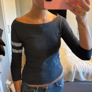 Djurgården långärmad topp marinblå - Säljer en marinblå trekvarts topp från Djurgårdens IF med ljusblåa ränder på ena ärmen och stort tryck med klubbens logga på sidan. Toppen har en tight passform och bred, rundad halsringning. Perfekt för dig som vill visa ditt DIF-stöd med stil.