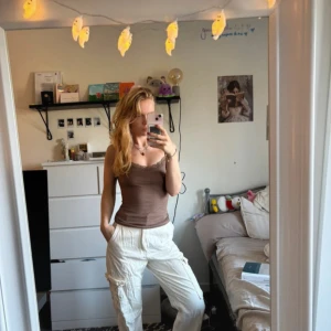 Vita cargopants med fickor, strl 38 - Säljer ett par vita cargopants i storlek 38 med flera praktiska fickor på sidorna. Byxorna har en avslappnad passform och är perfekta för en chill och trendig look. Materialet känns som bomull och de har en midwaist-modell. Snygga att styla med crop top eller hoodie.