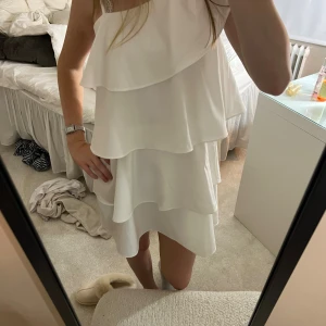 Vit volangklänning oneshoulder från Gina Tricot - Supersöt vit kortklänning med flera lager volanger och oneshoulder-design. Använt 2 ggr