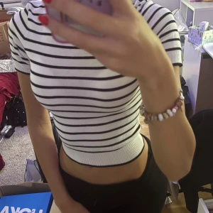 Vit och svart randig croppad topp - Säljer en vit och svart randig croppad topp med korta ärmar och rund hals. Toppen har en slim passform och är ribbad vid nederkant och ärmslut. Perfekt för dig som gillar enkel och stilren design med lite edge.