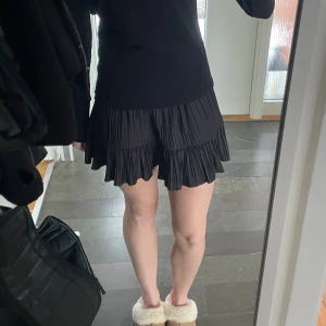 Svart plisserad volangkjol Zara - Supersnygg svart kortkjol med plisserat tyg och volangkant. 