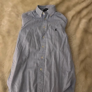 Blå skjorta från Polo Ralph Lauren - Klassisk ljusblå skjorta från Polo Ralph Lauren med button down-krage och broderad logga på bröstet. Skjortan har långa ärmar, knappar framtill och är tillverkad i mjuk bomull. Perfekt för en clean och stilren look. stryker och tvättar innan jag fraktar😉 använd typ 2 gånger, pris kan diskuteras