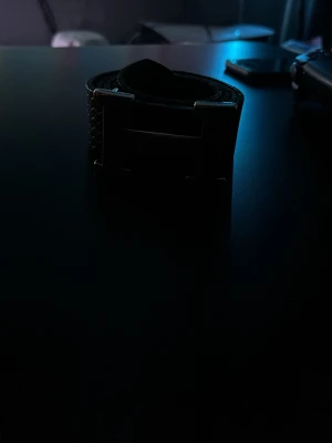 Svart H-bälte - Säljer en svart väst med ett stort, fyrkantigt metallspänne framtill. Västen har en robust känsla och är tillverkad i ett material som ser ut som skinn. Perfekt för dig som gillar en edgy stil och vill ha något som sticker ut.