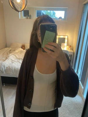 Brun stickad kofta från Lindex - Säljer en super fin brun, tjock stickad kofta med stora knappar eftersom jag inte riktigt använder den längre. Den är enkel att klä upp och ner och håller mig jätte varm nu på vintern. Allt är i jätte bra skick eftersom jag endast har använt den några gånger. Koftan är i storlek 10-12 men är ganska oversized så passar mig som 16 åring