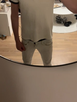 Vit Moncler pikétröja med mörka detaljer - Säljer en stilren vit pikétröja från Moncler med mörkblå krage och ärmslut. Tröjan har korta ärmar, klassisk pikékrage och knappar framtill. Moncler-logga broderad på bröstet. Perfekt för dig som gillar enkel och snygg design.