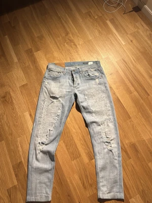 Ljusblå ripped jeans från dondup , strl 32 - Säljer ett par ljusblå jeans från Ritchie i storlek 32. De har en skinny passform och är rejält slitna med stora ripped-detaljer framtill och mindre slitningar bak. Klassisk femficksmodell med ljus tvätt och coola sömmar. Perfekta för dig som gillar streetstyle.