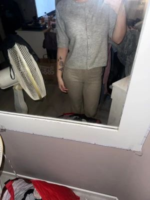 Grå stickad kofta från Lager 157 - Säljer en ljusgrå stickad kofta/tröja från Lager 157 med korta ärmar och rund hals. Koftan har pärlknappar framtill och är i mjukt material som känns skönt mot huden. Perfekt att slänga på sig när det är lite kyligt ute.