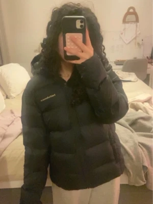 Marinblå dunjacka Peak Performance 160 - Säljer en svart dunjacka från Peak Performance i storlek 160. Jackan är fluffig och har huva, dragkedja och fickor. Perfekt för vinter och kallt väder. Har köpt från Länna sport då den kostade mig 2500kr men den passade inte som önskan så den är knappt använd och den är i unisex. Modellen är ”JD FROST DOWN PUFFER JACK”