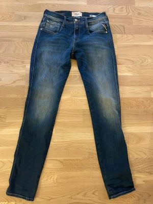 Replay Anbass Hyperflex jeans blå - Snygga Replay Anbass Hyperflex jeans i mörkblå tvätt med klassiska fem fickor och coola detaljer som kontrastsömmar och broderad logga på bakfickan. Stretchigt material för skön passform och smal siluett. Perfekt för dig som gillar stilrena jeans med lite edge. Skick 8/10. Kontakta mig för fler bilder