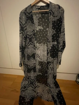 Svart och vit overshirt från Noisy May - Säljer en lång, svart och vit overshirt från Noisy May med paisley- och prickigt mönster. Jackan är tunn och har långärmad design, perfekt att slänga över en t-shirt för en chill look. Materialet känns lätt och luftigt.